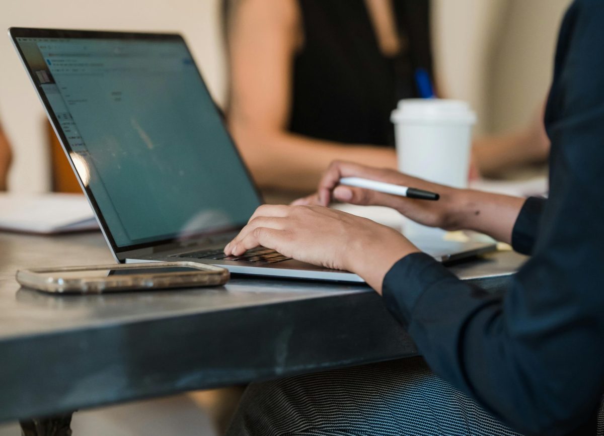 Professional woman typing on a laptop in a modern office environment.