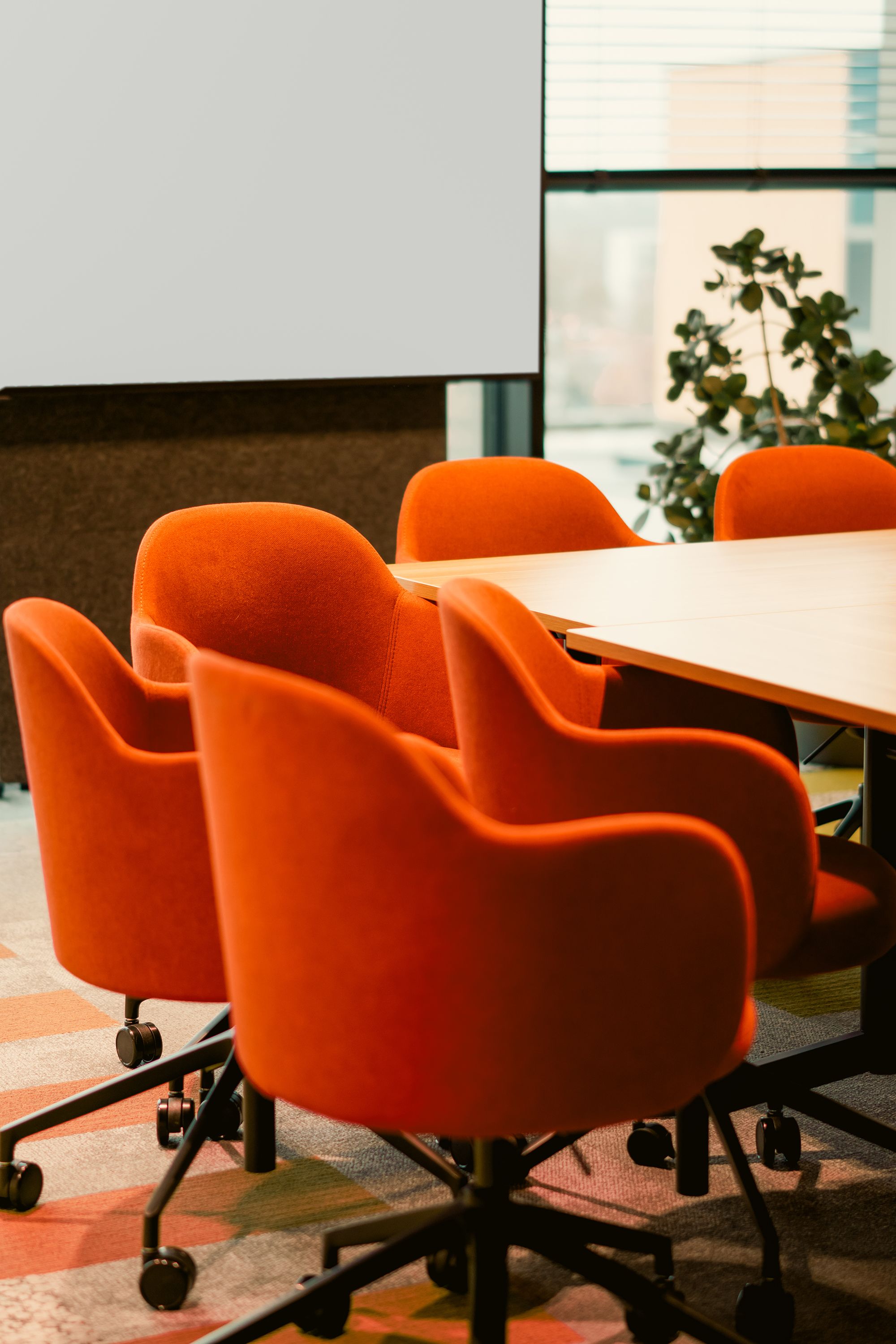 Contemporary office conference room featuring bright orange chairs and large window.